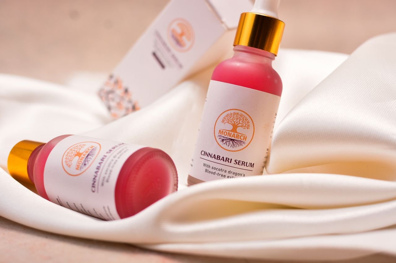 Elegant close-up of Cinnabari serum bottles on white fabric, showcasing luxury skincare packaging.