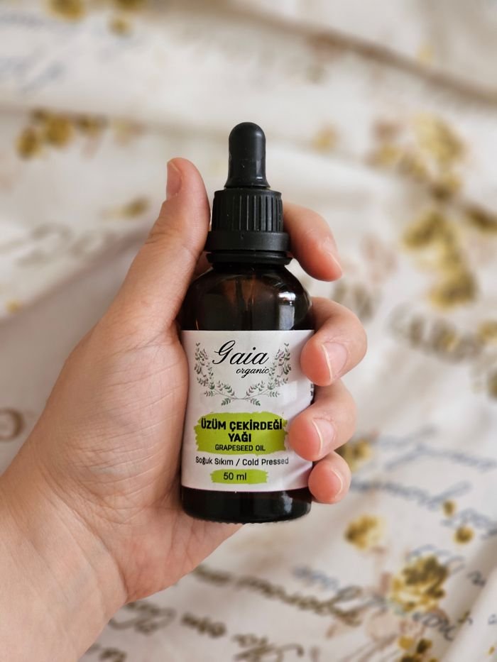 Close-up of a hand holding a bottle of Gaia organic grapeseed oil, perfect for skincare.