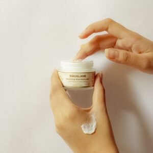 Close-up of hands applying squalane cream, highlighting skincare essentials.