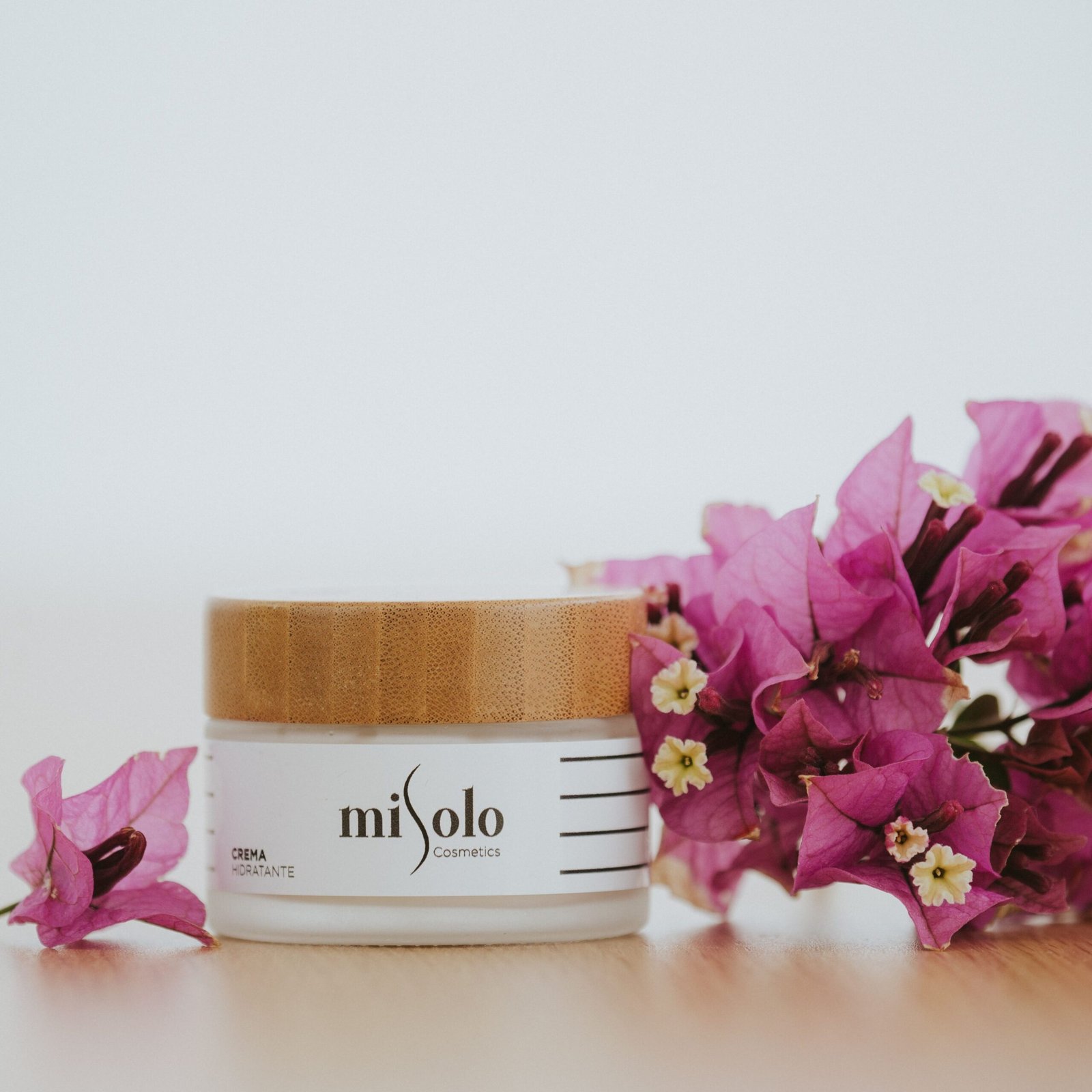 Luxurious cream in a bamboo jar surrounded by vibrant bougainvillea flowers.